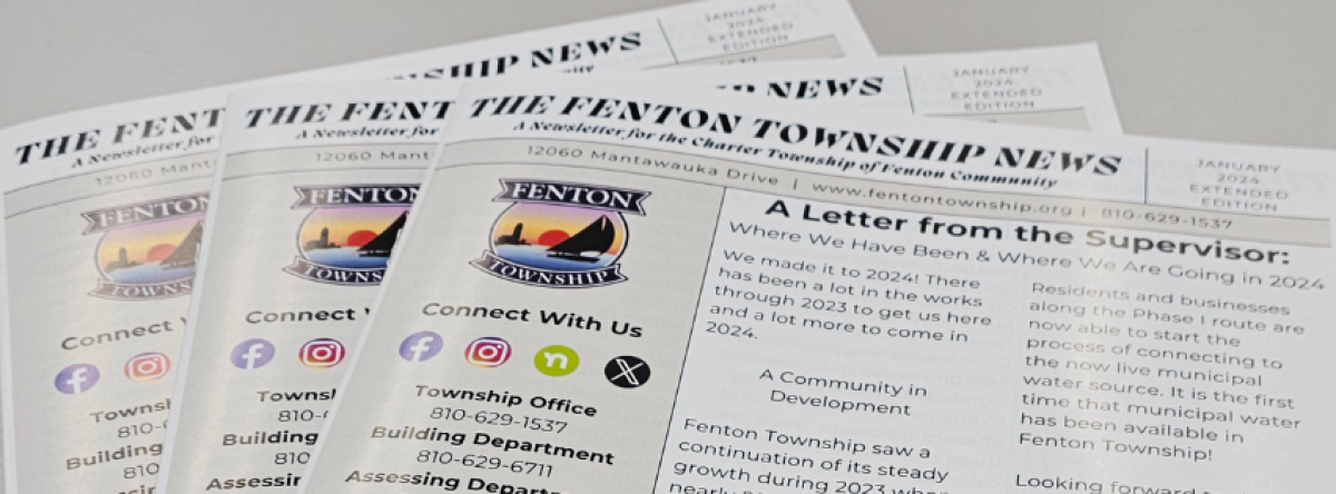 Picture of copies of The Fenton Township News fanned out on a table.