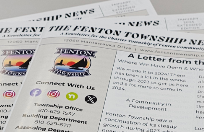 Picture of copies of The Fenton Township News fanned out on a table. 