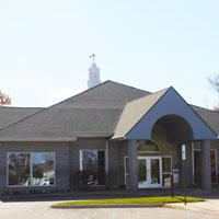 Gray brick building with gray tone shingles and blue texture highlights against a blue sky 