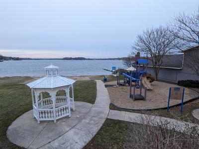 White gazebo in the foreground with Lake Fenton in the background. Mantawauka Park playground to the right.