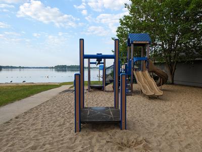 play structure in sand with lake in background