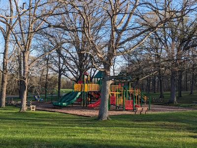 Bright multi colored playground with grass and trees around it